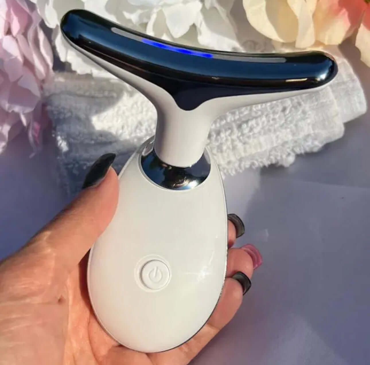 Beauty Device Anti Wrinkles held in hand with soft towels in the background.