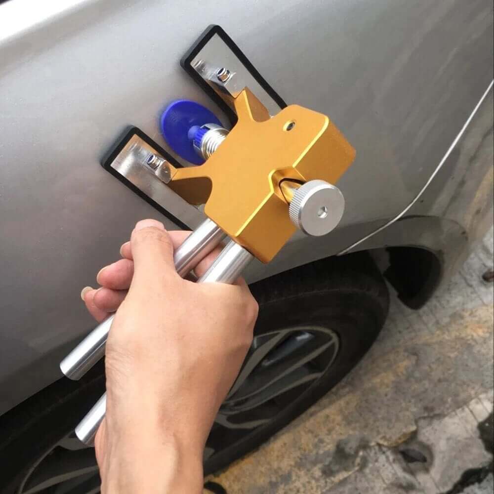 Paintless car dent repair tool being used to remove a dent from a car's finish.