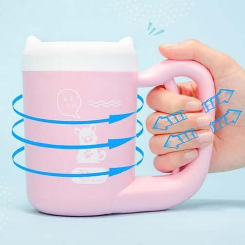 Hand holding a pink portable dog paw cleaner mug with cute cat ears and playful design elements.